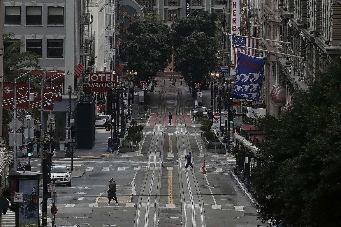 Pedestrians cross an empty Powell Street in San Francisco, Sunday, March 29, 2020. Californians endured a weekend of stepped-up restrictions aimed at keeping them home as much as possible while hospitals and health officials scrambled Sunday to ready themselves for a week that could see the feared dramatic surge in coronavirus cases.  (AP Photo/Jeff Chiu)