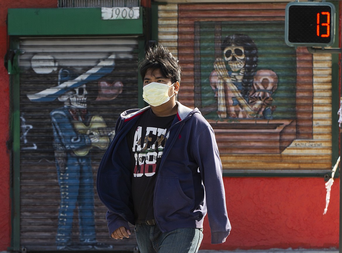 A pedestrian wears a face mask in the Boyle Heights area of Los Angeles on Wednesday, April 1, 2020. Los Angeles Mayor Eric Garcetti has recommended that the city's 4 million people wear masks when going outside amid the spreading coronavirus. Garcetti on Wednesday said people in the nation's second-largest city who are performing essential tasks such as food shopping should wear homemade, non-medical face coverings, or even bandannas. (AP Photo/Damian Dovarganes)