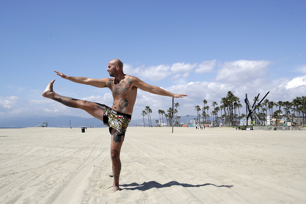 Michael Holt practices Tai Chi on a deserted Venice Beach Sunday, March 29, 2020, in Los Angeles. With cases of coronavirus surging and the death toll increasing, lawmakers are pleading with cooped-up Californians to spend a second weekend at home to slow the spread of the infections. (AP Photo/Marcio Jose Sanchez)