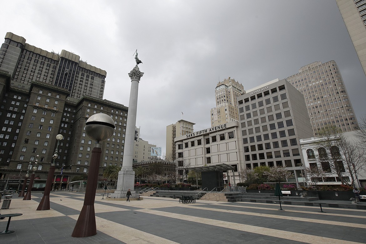 A pedestrian walks through a nearly empty Union Square in San Francisco, Sunday, March 29, 2020. Californians endured a weekend of stepped-up restrictions aimed at keeping them home as much as possible while hospitals and health officials scrambled Sunday to ready themselves for a week that could see the feared dramatic surge in coronavirus cases. (AP Photo/Jeff Chiu)
