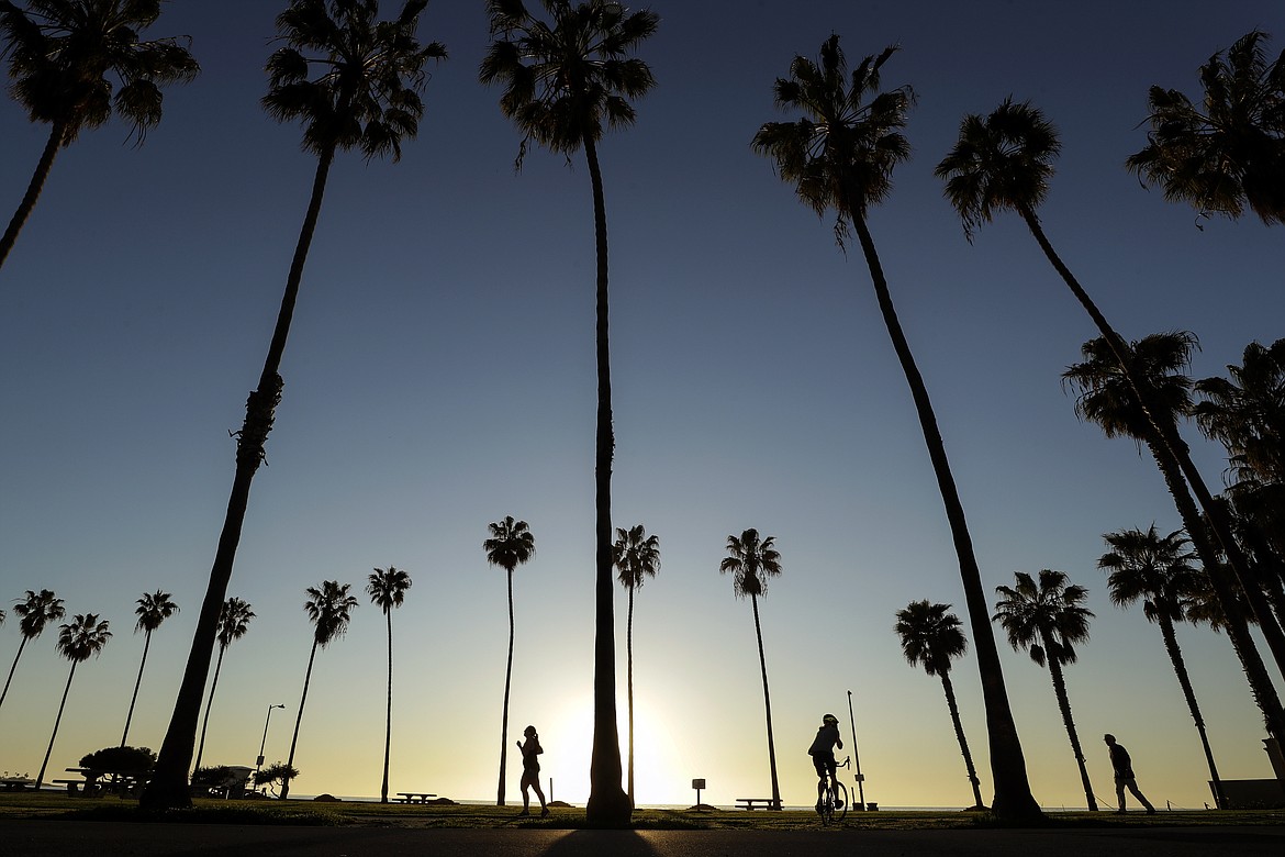 People keep their distance as they exercise outside of a closed La Jolla beach Wednesday, April 15, 2020, in San Diego. (AP Photo/Gregory Bull)