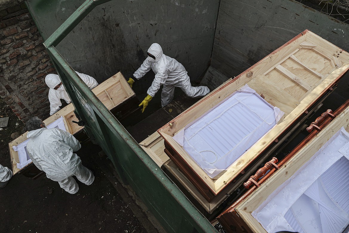 Workers collect and stack the coffins of people that have been recently cremated amid the new coronavirus pandemic, at the La Recoleta cemetery in Santiago, Chile, Sunday, June 28, 2020. The coffins are collected, destroyed, and processed by a company specialized in organic waste. (AP Photo/Esteban Felix)