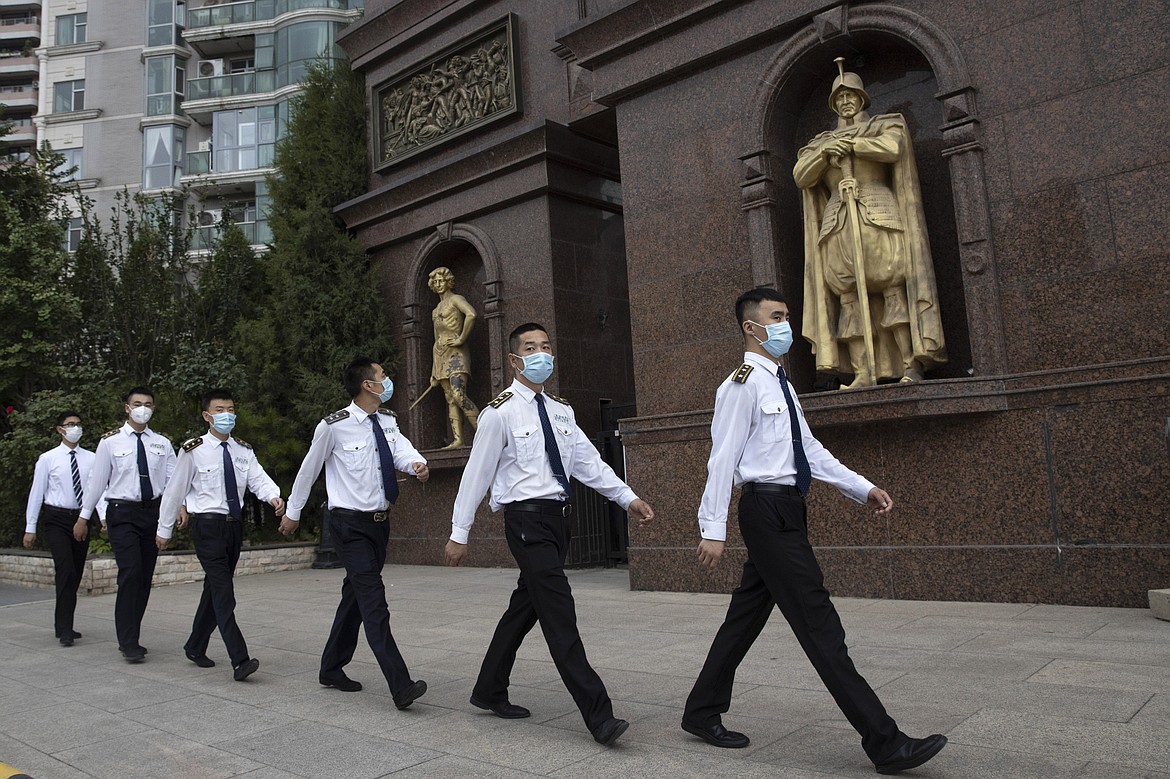 Security guards wearing masks to curb the spread of the coronavirus march past a community with European style statues in Beijing on Monday, June 29, 2020. Even as the world surpassed two sobering coronavirus milestones Sunday -- 500,000 confirmed deaths, 10 million confirmed cases -- and hit another high mark for daily new infections, China on Monday reported a further decline in new confirmed cases. (AP Photo/Ng Han Guan)