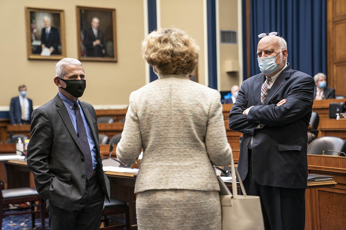 Director of the National Institute of Allergy and Infectious Diseases Dr. Anthony Fauci, left, and Dr. Robert Redfield, director of the Centers for Disease Control and Prevention, right, talk with members of congress before a House Committee on Energy and Commerce on the Trump administration's response to the COVID-19 pandemic on Capitol Hill in Washington on Tuesday, June 23, 2020. (Sarah Silbiger/Pool via AP)