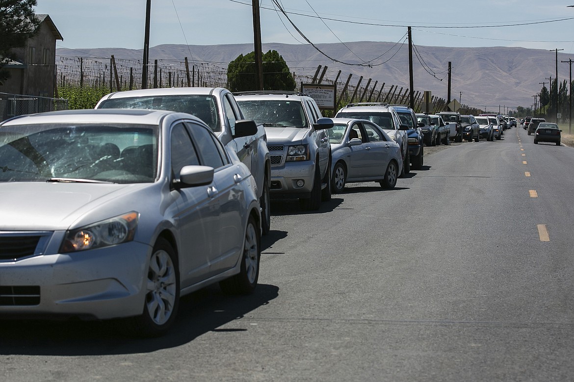 In this photo taken Friday, June 26, 2020, vehicles line up for a drive-thru distribution of food and emergency supplies hosted by the Peacekeeper Society in Harrah, Wash. While the pandemic at first pounded the greater Seattle area, the epicenter has now moved east across the Cascade Range. Washington is seeing rising cases of COVID-19, driven in large part by increasing numbers in Yakima, Benton, Franklin and Spokane counties, the largest communities in eastern Washington.(Amanda Ray/Yakima Herald-Republic via AP)