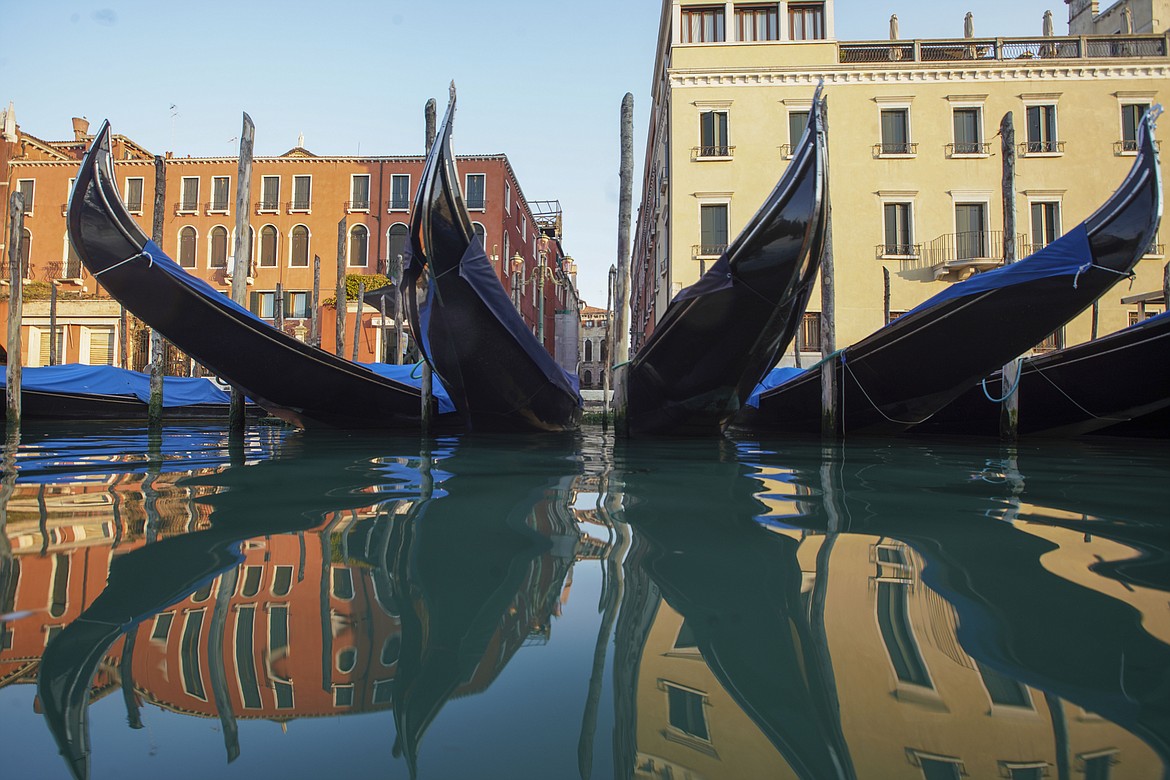 FILE - In this Monday, April 6, 2020 file photo, moored gondolas are reflected on the water of the Gran Canal, in Venice. The European Union announced Tuesday, June 30, 2020 that it will reopen its borders to travelers from 14 countries, but most Americans have been refused entry for at least another two weeks due to soaring coronavirus infections in the U.S. (AP Photo/Andrew Medichini, File)