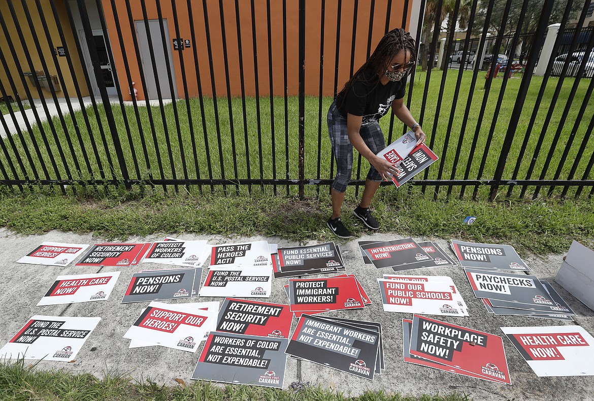 Kelli Ann Thomas, a candidate for Community Council, sorts signs before the start of a Workers First Caravan, Wednesday, June 17, 2020, in Miami. The caravan was part of a nation-wide effort to urge those in government to implement policies that further economic and racial justice. (AP Photo/Wilfredo Lee)