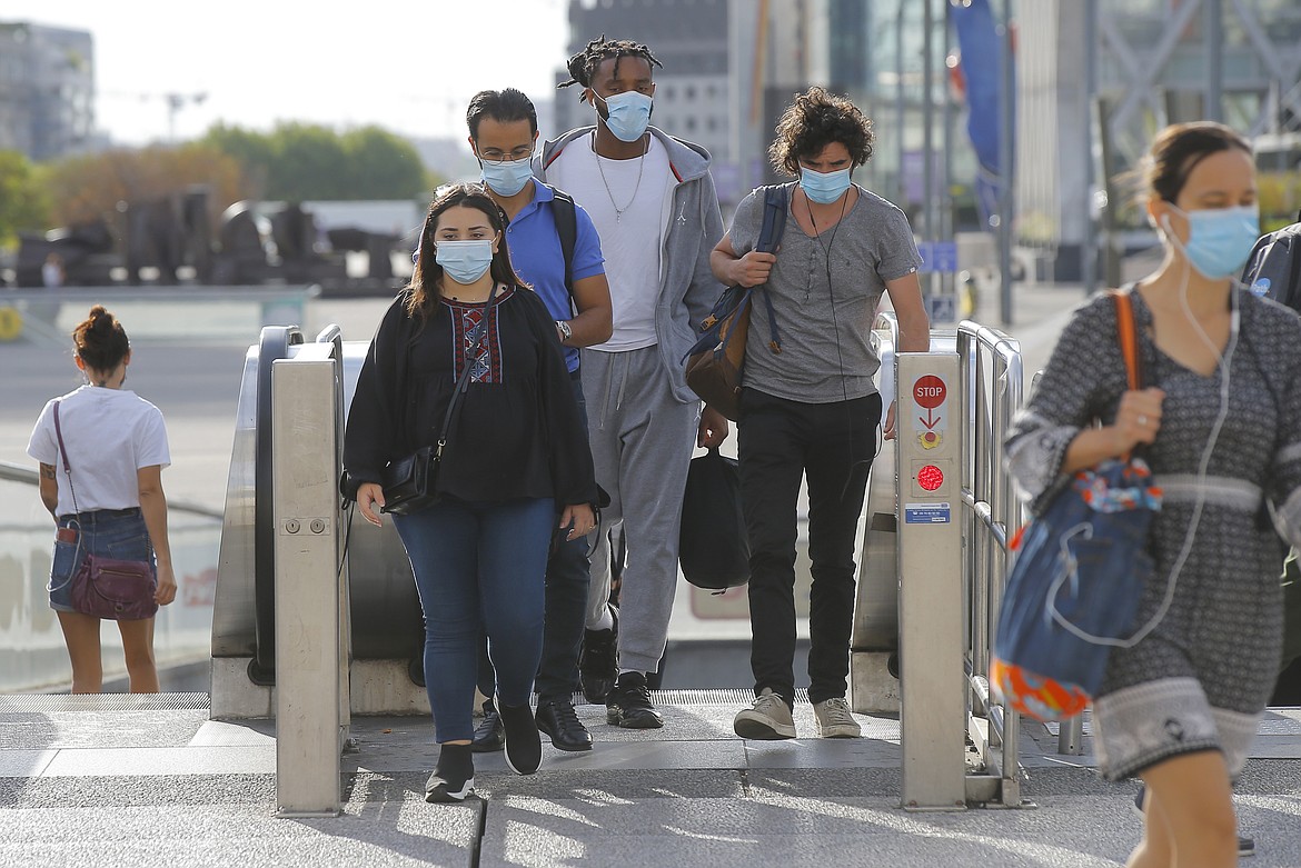 People walk out of a transportation hub at La Defense business district while wearing a protective face masks as a precaution against the coronavirus, in Paris, Friday, Aug. 21, 2020. France's president insisted that the country will send millions of students back to school starting Sept. 1, despite the biggest weekly spike in virus infections since the height of the crisis in March and April. (AP Photo/Michel Euler)