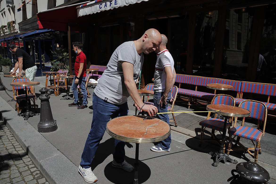 Waiters prepare the terrace of a restaurant in order to respect distancing measures in Paris, Monday, June 1, 2020, as France gradually lifts its Covid-19 lockdown. France is reopening tomorow its restaurants, bars and cafes as the country eases most restrictions amid the coronavirus crisis. (AP Photo/Christophe Ena)