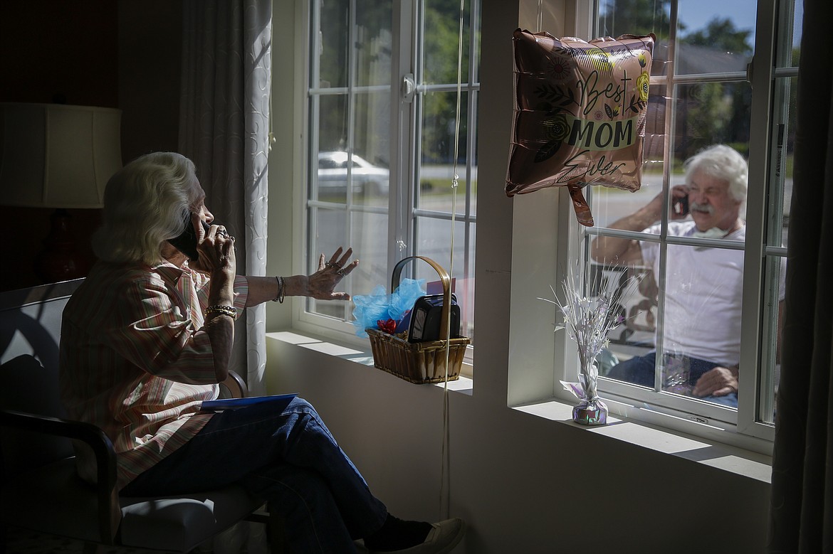 Mary Faye Cochran, 86, sings "You Are My Sunshine" over the phone to her son Stacey Smith through a window for a Mother's Day celebration at Provident Village at Creekside senior living on Sunday, May 10, 2020, in Smyrna, Ga. (AP Photo/Brynn Anderson)