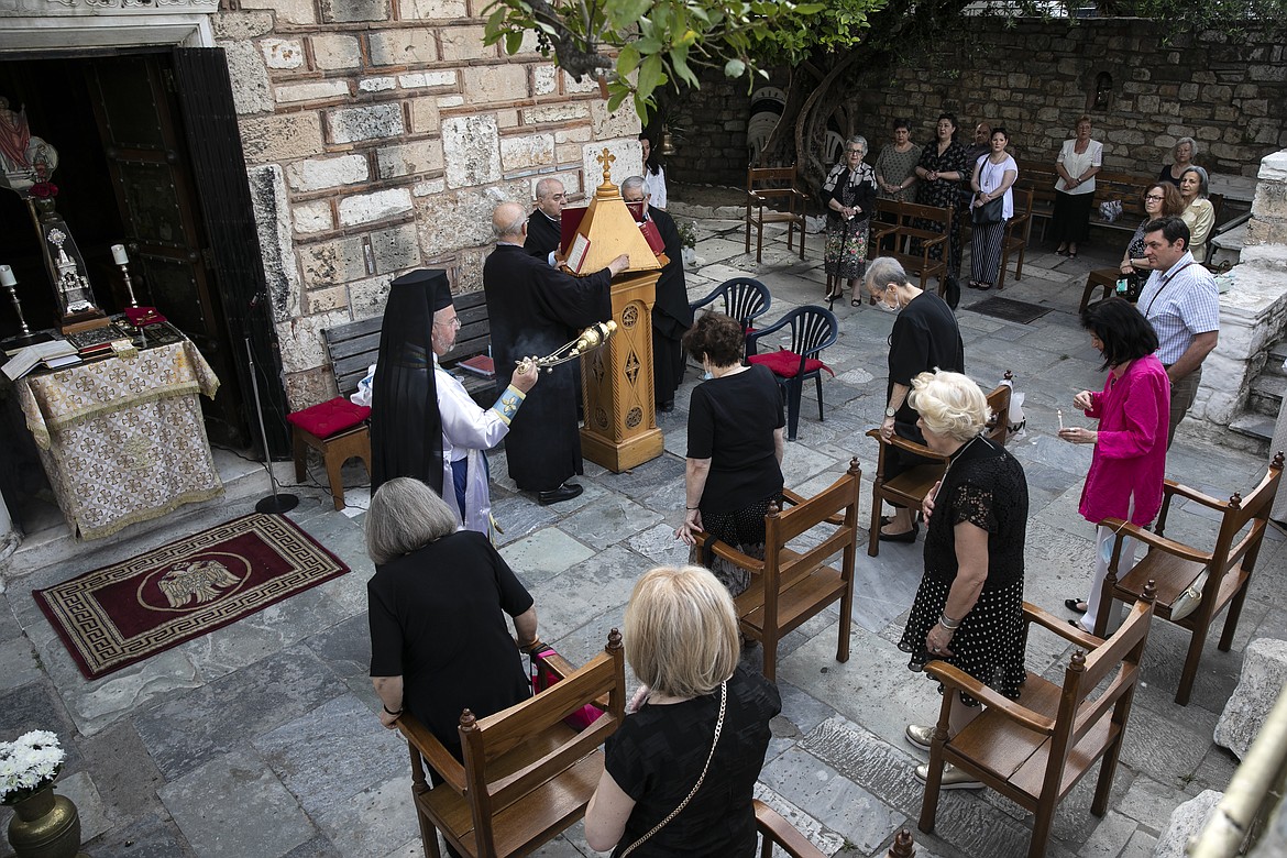 An Orthodox priest swings a chain censer in front of faithful during a Sunday mass taking place outside a church, in Athens, Sunday, May 17, 2020. Greek government allowed churches throughout the country to reopen their doors to faithful on Sunday, a decision that applies to regular services and ceremonies like baptisms and weddings. (AP Photo/Yorgos Karahalis)