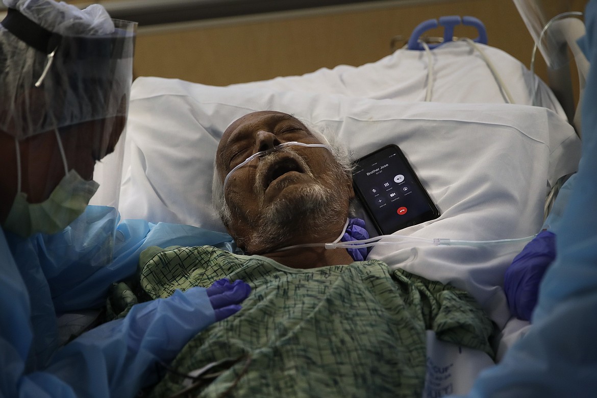 A phone is placed next to Antonio Navarro, a 65-year-old COVID-19 patient, for his son, Jose, to say goodbye to him in his final moments as Navarro's wife, Romelia, left, weeps at his bedside at St. Jude Medical Center in Fullerton, Calif., Friday, July 31, 2020. Navarro was nurse Michel Younkin's first COVID-19 patient to pass on her watch. (AP Photo/Jae C. Hong)