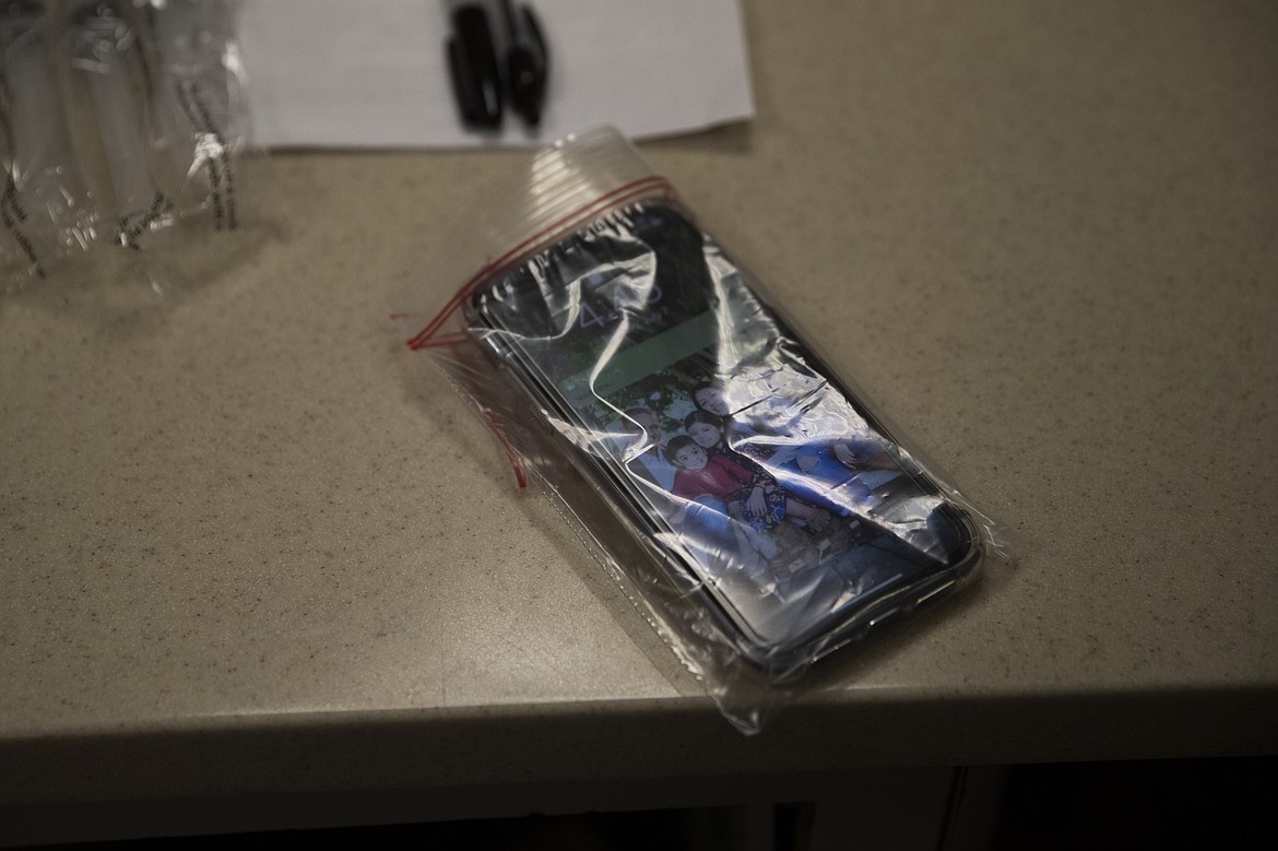 Wrapped in a resealable plastic bag, a smartphone belonging to nurse Jackie Vargas, who works in St. Jude Medical Center's COVID-19 unit, displays her family portrait in Fullerton, Calif., Tuesday, July 7, 2020. (AP Photo/Jae C. Hong)