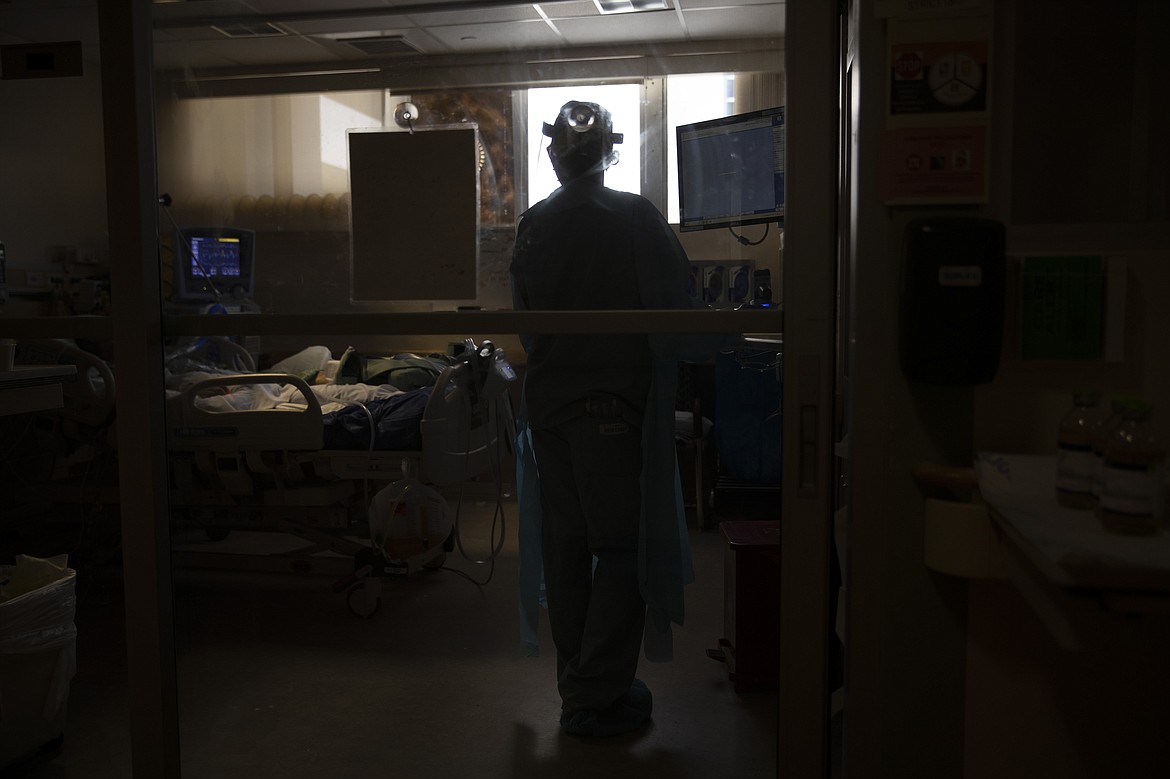 Nurse Jackie Vargas looks at a COVID-19 patient in critical condition while working on a computer at St. Jude Medical Center in Fullerton, Calif., Tuesday, July 7, 2020. (AP Photo/Jae C. Hong)
