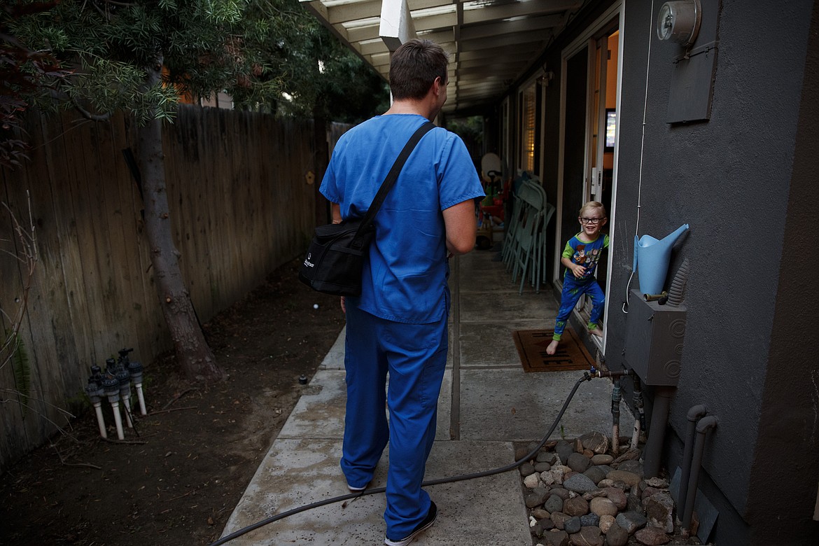 James Cushing, 3, pops out of a door to greet his father, Spencer, a 29-year-old nurse who works in St. Jude Medical Center's COVID-19 unit, in Orange, Calif., Monday, July 13, 2020. For the month of April, the Cushing family lived apart. Cushing spent his days and some of his nights at St. Jude's, as a nurse caring for "step-down" patients recovering from the most serious COVID-19 symptoms. (AP Photo/Jae C. Hong)