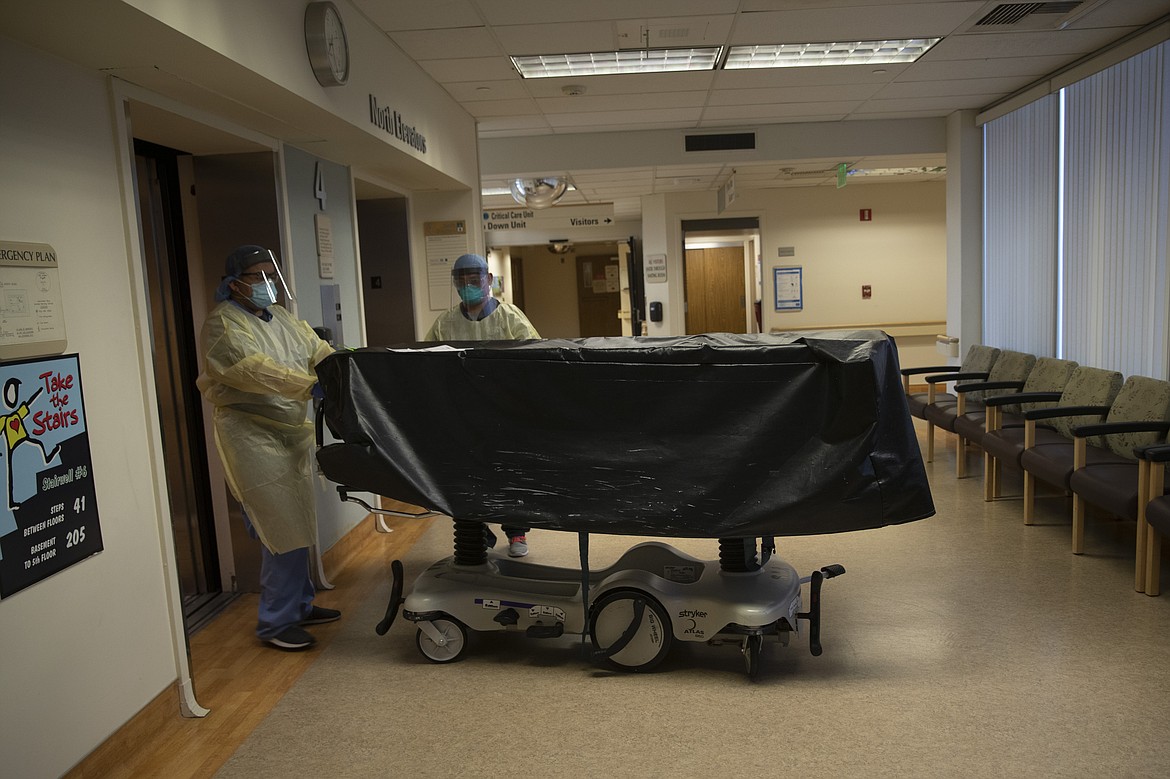 Two hospital staff enter an elevator with the body of a COVID-19 victim on a gurney at St. Jude Medical Center in Fullerton, Calif., Tuesday, July 7, 2020. (AP Photo/Jae C. Hong)