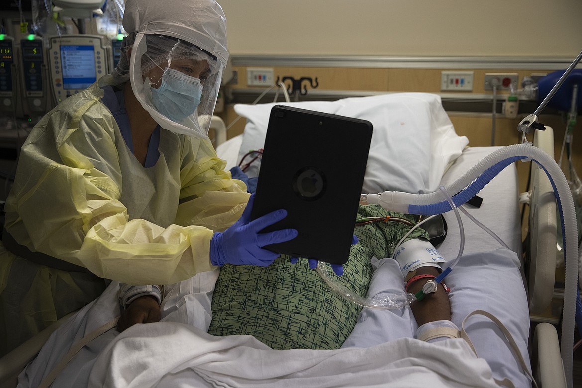 Nurse Shamaine Santos holds an iPad for family members of a sedated COVID-19 patient during a video chat at St. Jude Medical Center in Fullerton, Calif., Tuesday, July 7, 2020. The pandemic rages on and cases climb throughout California, once again one of the nation's hot spots. The nurses forge ahead. (AP Photo/Jae C. Hong)
