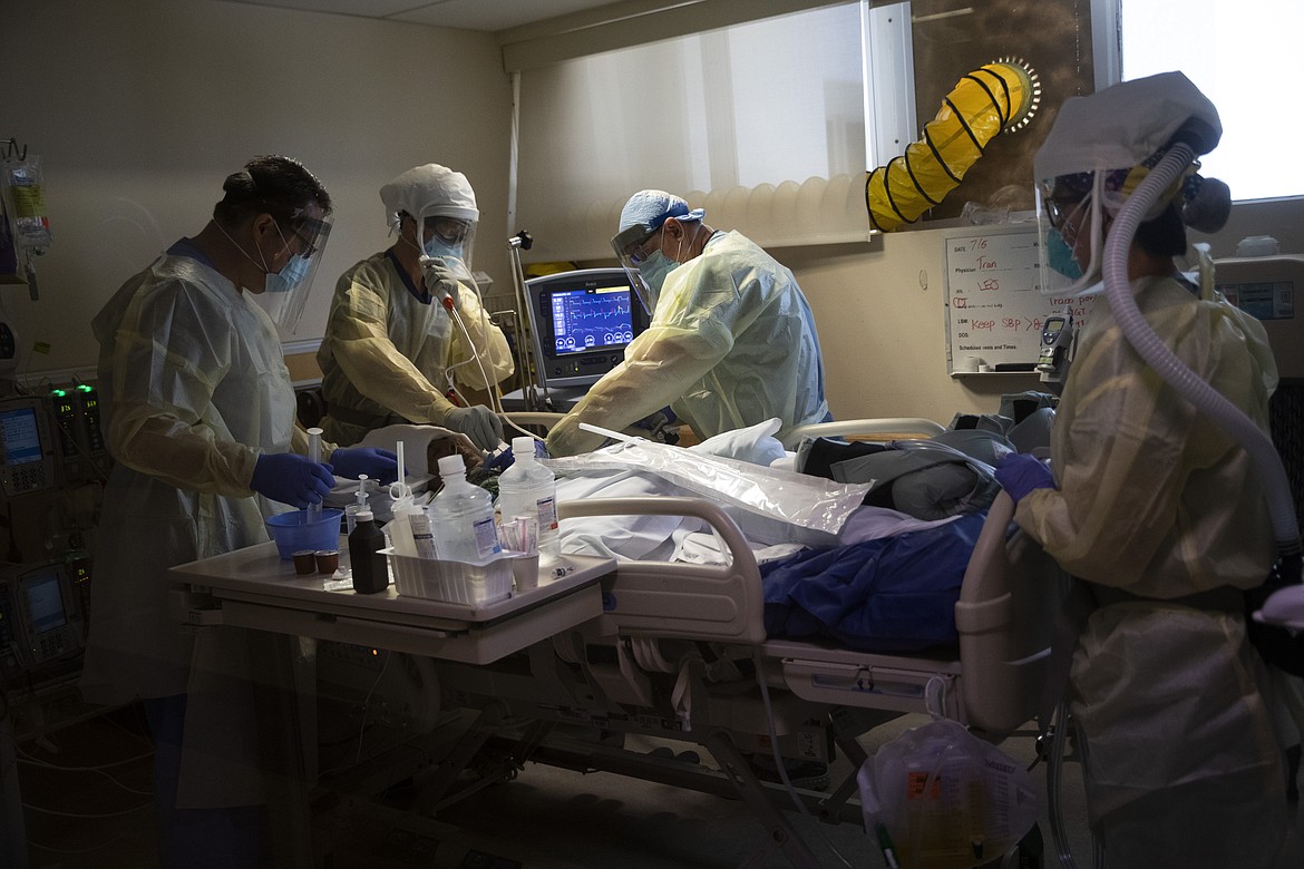 Nurse Jackie Vargas, far right, watches as Dr. Michael Katz, second from left, performs a procedure on a critically ill COVID-19 patient with Juan Herrera, left, and Kevin Neal at St. Jude Medical Center in Fullerton, Calif., Tuesday, July 7, 2020. (AP Photo/Jae C. Hong)