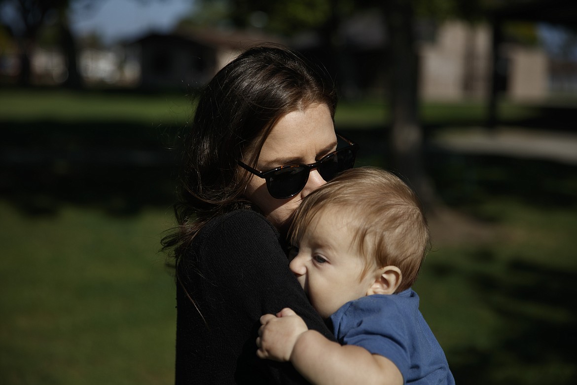 Michele Younkin, a 28-year-old nurse who works in a COVID-19 unit at St. Jude Medical Center, kisses her 7-month-old son, Jackson, in a park on her day off in Garden Grove, Calif., Wednesday, Aug. 5, 2020. On the fifth day after her patient died of the coronavirus, Younkin's voice breaks as she sits cross-legged on a blanket during a sunny day in the park with her husband and giggling infant son. (AP Photo/Jae C. Hong)