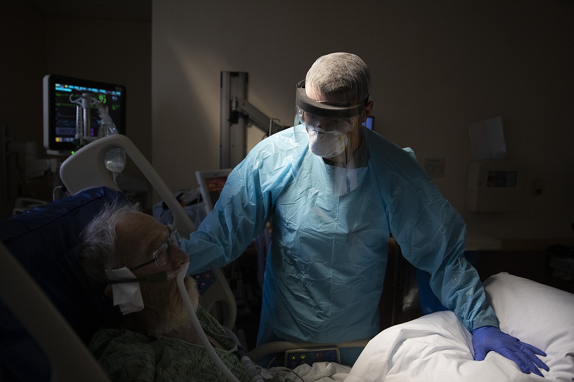 Spencer Cushing, 29, tends to David Feinour, a 71-year-old COVID-19 patient, at St. Jude Medical Center in Fullerton, Calif., Tuesday, July 7, 2020. For the month of April, the Cushing family lived apart. Cushing spent his days and some of his nights at St. Jude's, as a nurse caring for "step-down" patients recovering from the most serious COVID-19 symptoms. (AP Photo/Jae C. Hong)