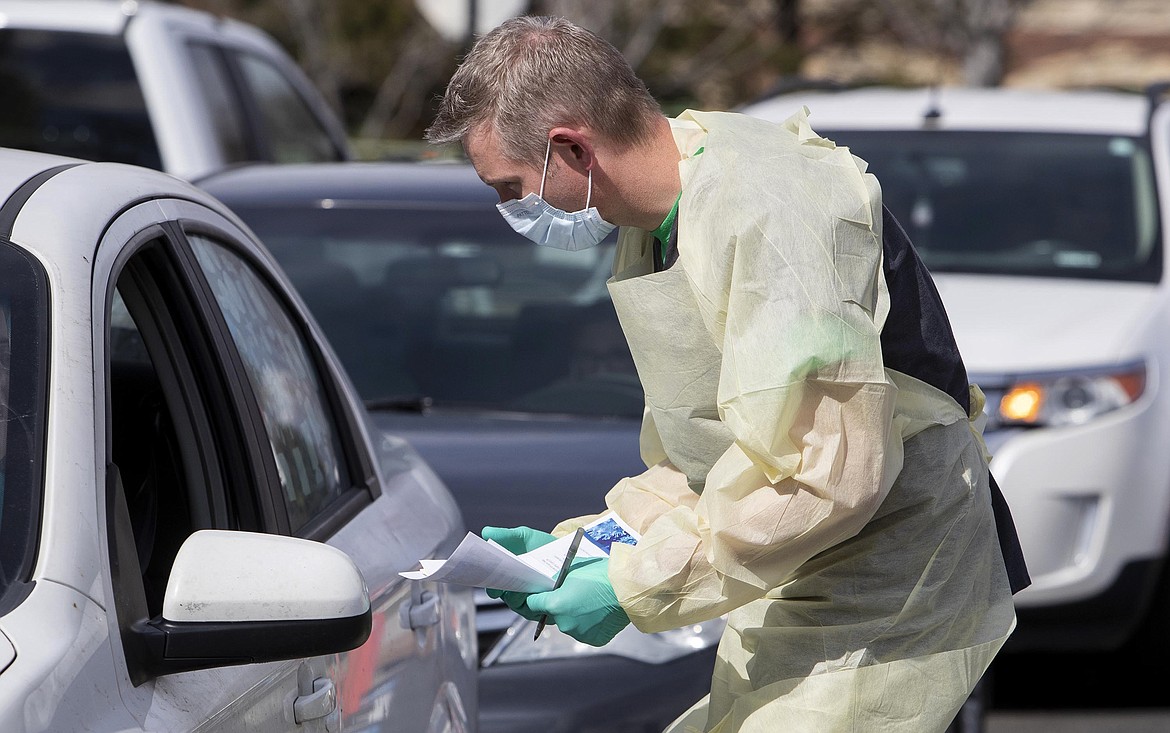 Nurse manager Cullen Anderson, RN, screens people in a line of cars waiting to be tested for COVID-19 coronavirus at a drive-thru testing station at St. Luke's Meridian Medical Center Tuesday, March 17, 2020 in Meridian Idaho. (Darin Oswald/Idaho Statesman via AP)