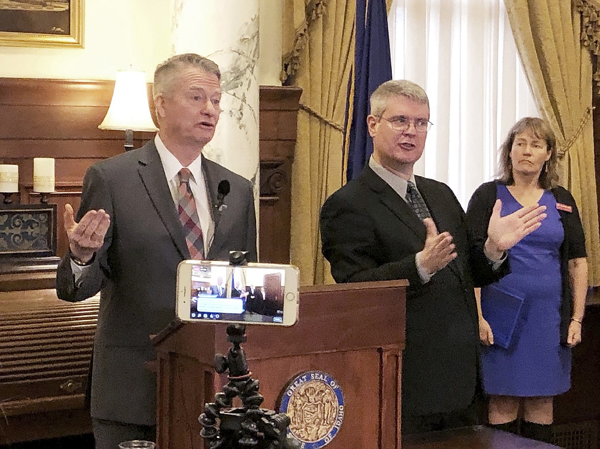 Idaho Gov. Brad Little, left, announces stricter guidelines for social interactions to slow the spread of the new coronavirus, and also livestreaming the discussion, at his ceremonial office in the Statehouse in Boise on Wednesday, March 18, 2020. Sign language interpreter Steven Stubbs is at center; state epidemiologist Christine Hahn is at right. For most people, the new coronavirus causes only mild or moderate symptoms. For some it can cause more severe illness, especially in older adults and people with existing health problems. (AP Photo/Keith Ridler)