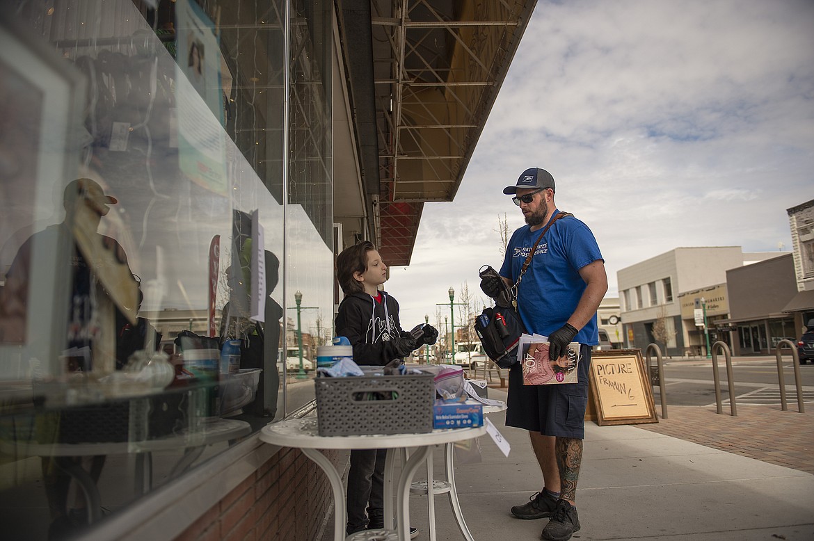 Dominic Babayan gives postal worker Chad Herdmann a mask to wear on Monday, April 6, 2020, outside of Ooh La La on Main Avenue in Twin Falls, Idaho.  (Drew Nash/Times-News via AP)