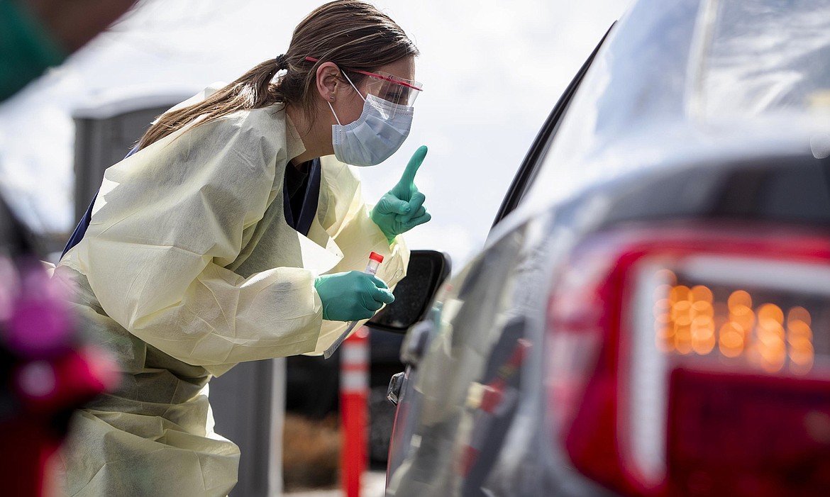 Ashley Layton, an LPN at St. Luke's Meridian Medical Center, communicates with a person before taking swab sample at a special outdoor drive-thru screening station for COVID-19   coronavirus Tuesday, March 17, 2020.  (Darin Oswald/Idaho Statesman via AP)