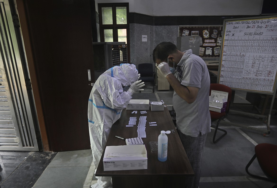Health workers arrange testing strips to test for COVID-19 in a government school in New Delhi, India, Thursday, Aug. 20, 2020. The country has the fourth-most deaths in the world and the third-most cases, with over 2.7 million, including more than 64,000 new infections reported Wednesday. (AP Photo/Manish Swarup)
