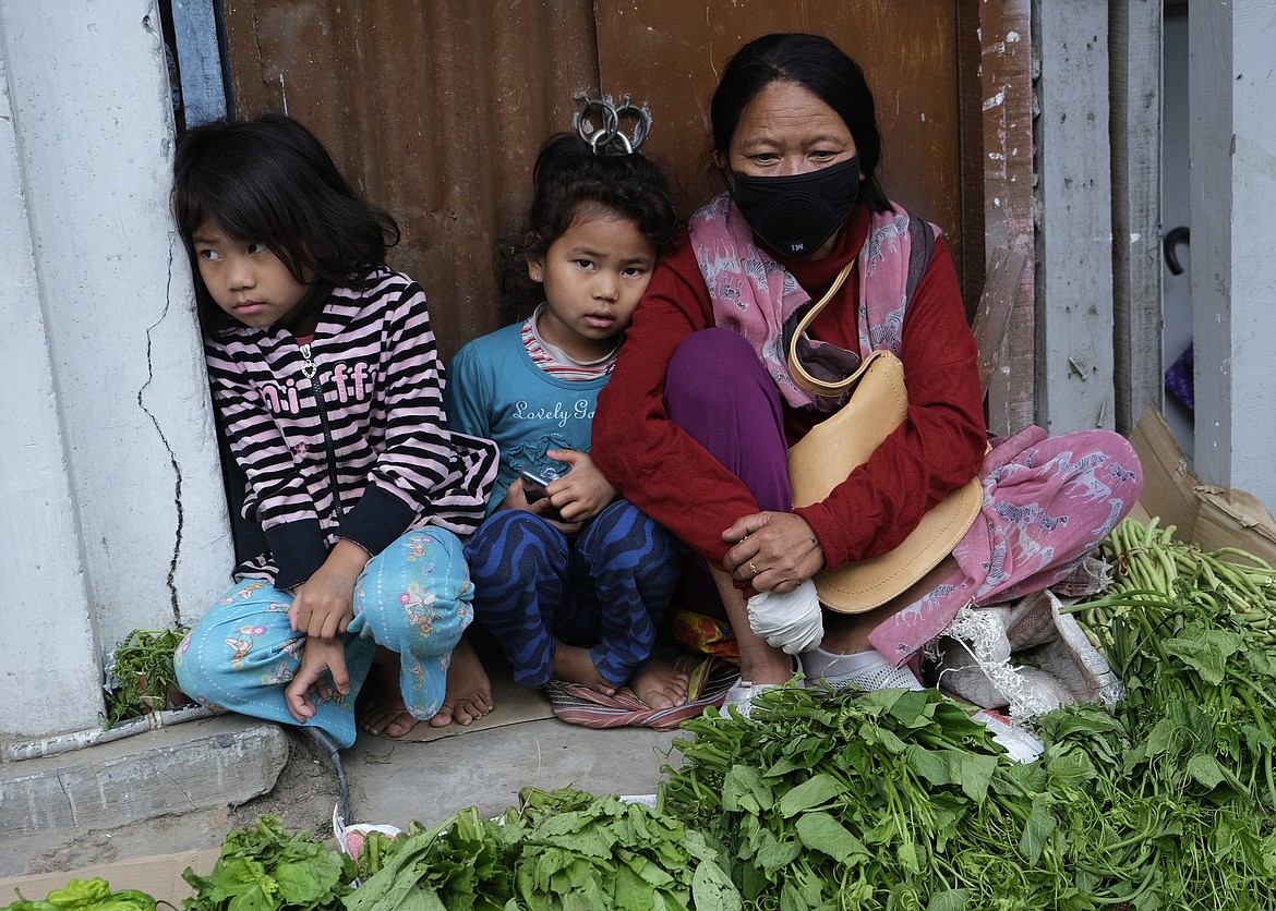 A family sits by the side of a road selling local vegetables in Kohima, capital of the northeastern Indian state of Nagaland, Wednesday, May 27, 2020. The state, which was a green zone until earlier this week, now has 9 COVID-19 positive cases. An uptick in cases has been reported in some of India’s northeastern states as migrant workers and students returning to native villages from India’s largest cities have begun arriving home on special trains. (AP Photo/Yirmiyan Arthur)
