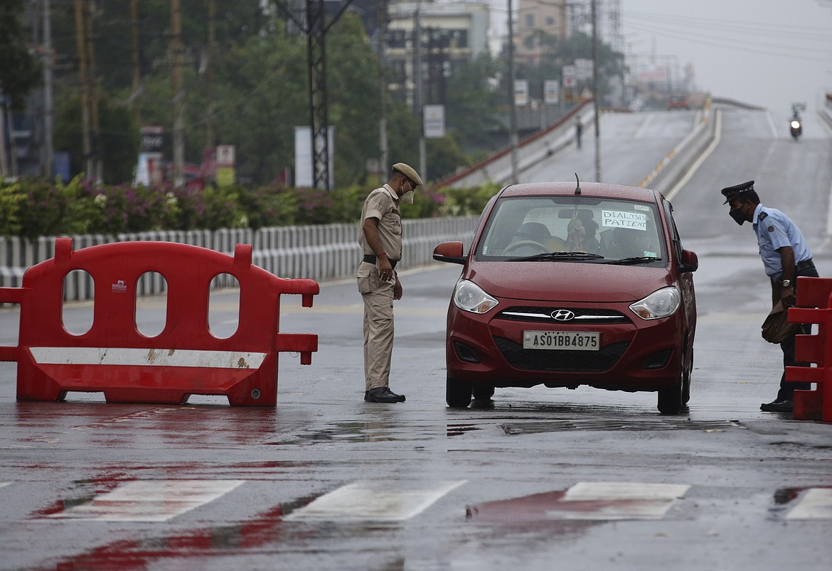 Indian policemen check a vehicle carrying a patient during the reimposed lockdown in Gauhati, India, Monday, June 29, 2020. India has reported a new daily record of nearly 20,000 new infections as several Indian states reimpose partial or full lockdowns to stem the spread of the coronavirus. (AP Photo/Anupam Nath)