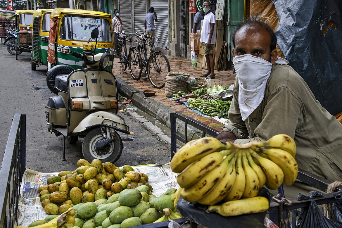 A street side fruit vendor has his face covered as a precaution against the coronavirus in Kolkata, India, Tuesday, July 21, 2020. With a surge in coronavirus cases in the past few weeks, state governments in India have been ordering focused lockdowns in high-risk areas to slow down the spread of infections. (AP Photo/Bikas Das)