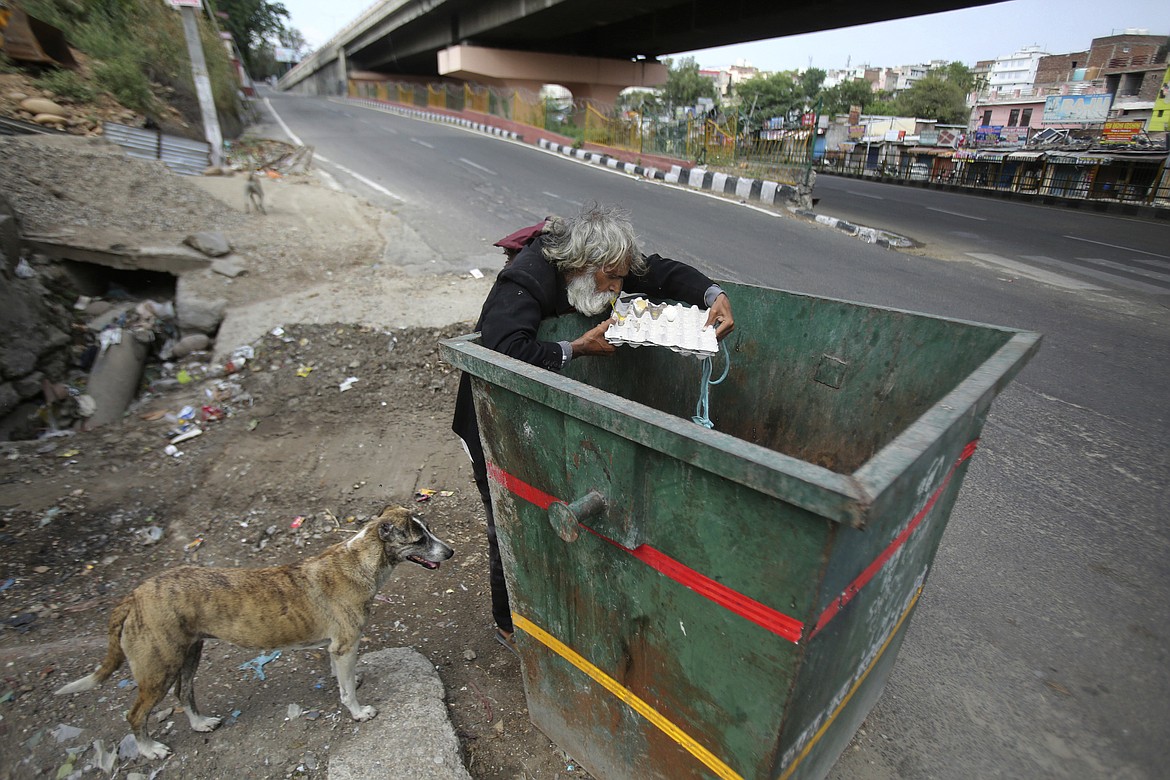An Indian homeless man eats eggs discarded in a garbage bin during lockdown to curb the spread of new coronavirus on the outskirts of Jammu, India, Sunday, May 10, 2020. India's lockdown entered a sixth week on Sunday, though some restrictions have been eased for self-employed people unable to access government support to return to work. (AP Photo/Channi Anand)