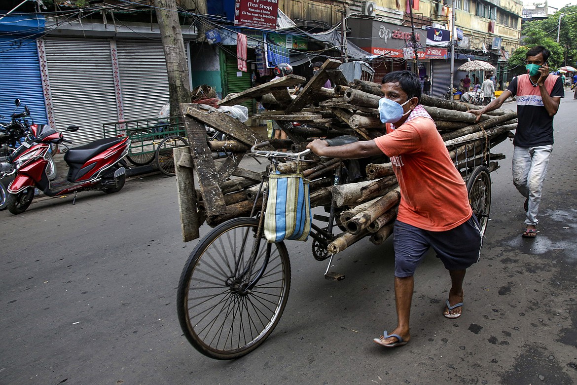 People wearing masks as a precaution against the coronavirus transport scrap on a rickshaw in Kolkata, India, Tuesday, July 21, 2020. With a surge in coronavirus cases in the past few weeks, state governments in India have been ordering focused lockdowns in high-risk areas to slow down the spread of infections. (AP Photo/Bikas Das)