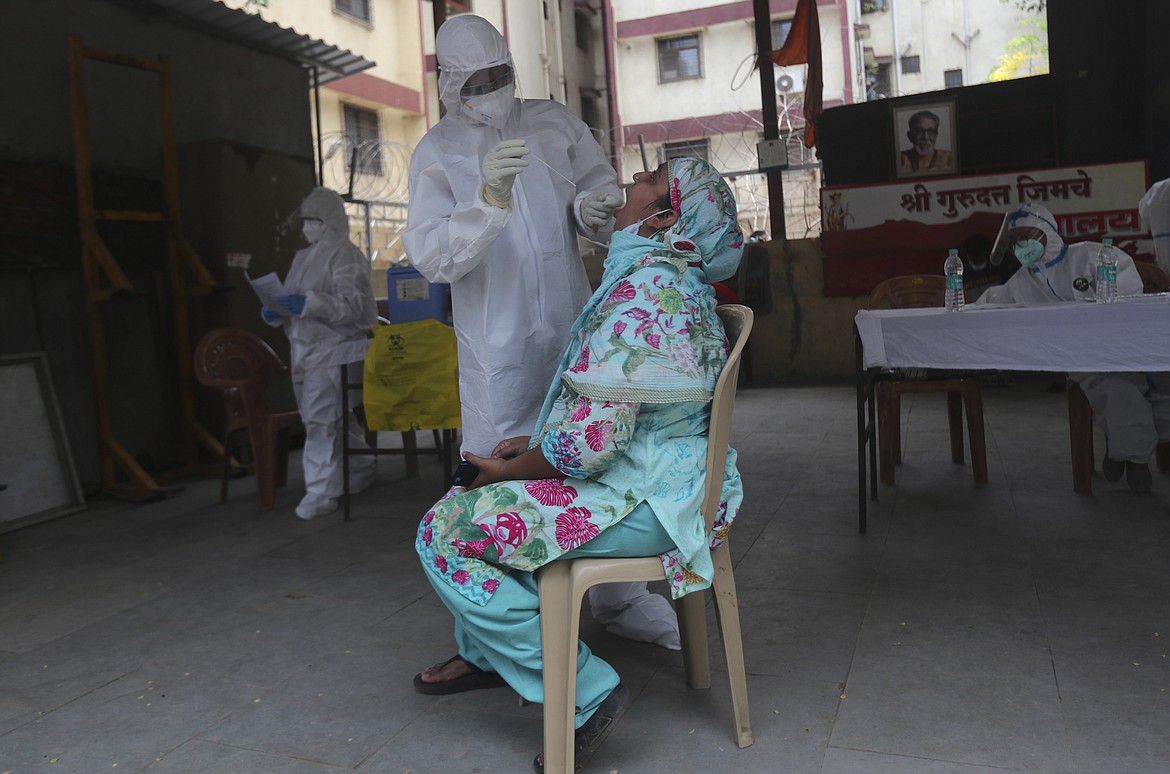 A health worker takes a swab test of a woman during a free medical checkup in Dharavi, one of Asia's biggest slums, in Mumbai, India, Friday, June 26, 2020. India is the fourth hardest-hit country by the pandemic in the world after the U.S., Russia and Brazil. (AP Photo/Rafiq Maqbool)