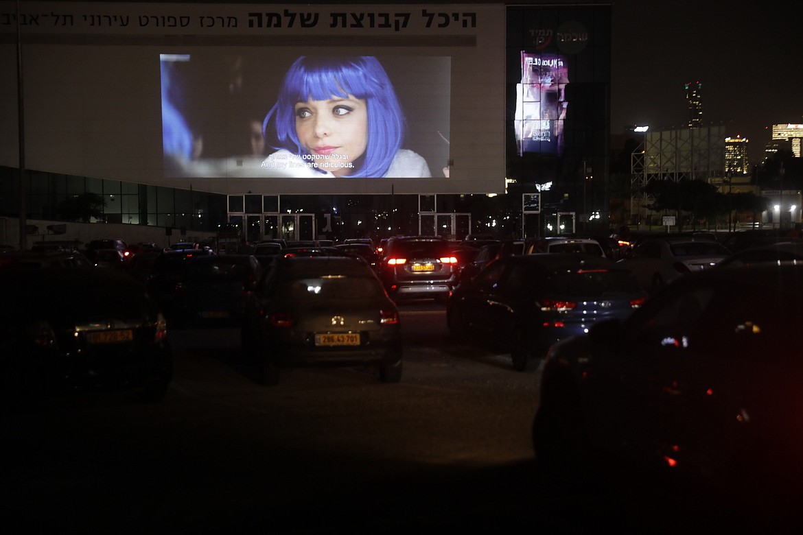 Israelis watch a movie from their car In Tel Aviv, Israel, Wednesday, Aug. 5, 2020. As movie theaters in Israel remain shut because of the coronavirus outbreak, Tel Aviv is bringing an old drive-in back to life for a few days this summer.   (AP Photo/Sebastian Scheiner)