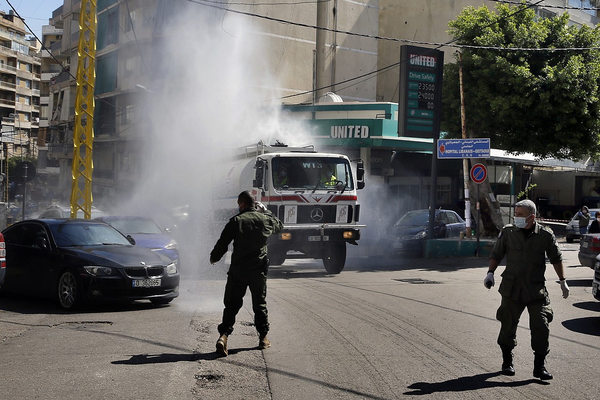 A municipal tanker sprays disinfectant as a precaution against the coronavirus outbreak in Beirut, Lebanon, Sunday, March 22, 2020. Lebanon has been taking strict measures to limit the spread of the coronavirus closing restaurants and nightclubs as well as schools and universities. (AP Photo/Bilal Hussein)