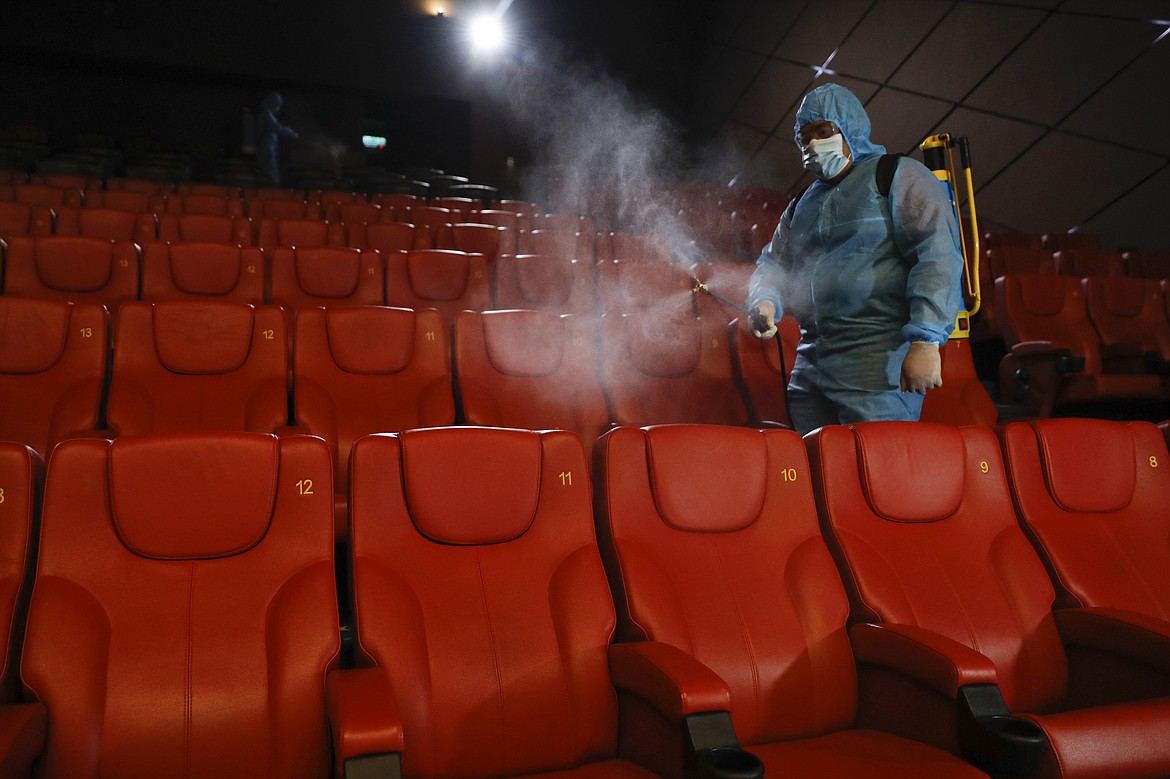 A staff member of a cinema sprays disinfectant at the cinema hall to prepare for reopening on July 1 in Kuala Lumpur, Malaysia, Friday, June 26, 2020. Malaysia entered the Recovery Movement Control Order (RMCO) after three months of coronavirus restrictions. (AP Photo/Vincent Thian)