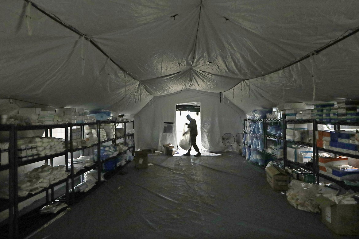 FILE - In this March 31, 2020, file photo a U.S. Army soldier walks inside a mobile surgical unit being set up by soldiers from Fort Carson, Col., and Joint Base Lewis-McChord (JBLM) as part of a field hospital inside CenturyLink Field Event Center, in Seattle. As of last week, the Army had already exceeded its retention goal of 50,000 soldiers for the fiscal year ending in September, re-enlisting more than 52,000 so far.  (AP Photo/Elaine Thompson, File)