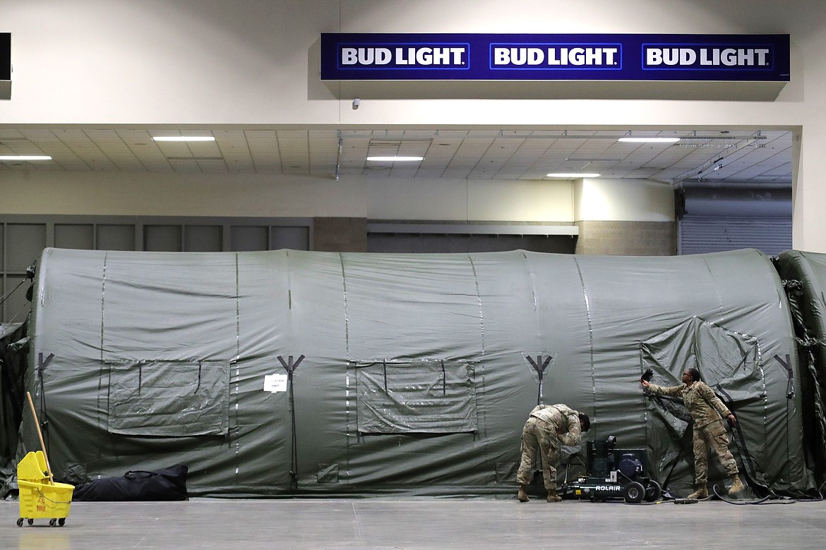 FILE - In this April 5, 2020, file photo soldiers work next to an isolation tent at a military field hospital at the CenturyLink Field Event Center in Seattle. As of last week, the Army had already exceeded its retention goal of 50,000 soldiers for the fiscal year ending in September, re-enlisting more than 52,000 so far. (AP Photo/Ted S. Warren, File)