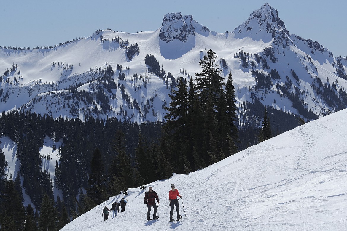 Snowshoers head up a slope above Paradise at Mount Rainier National Park, Wednesday, March 18, 2020, in Washington state. Most national parks are remaining open during the outbreak of the new coronavirus, but many are closing visitor centers, shuttles, lodges and restaurants in hopes of containing its spread. (AP Photo/Ted S. Warren)