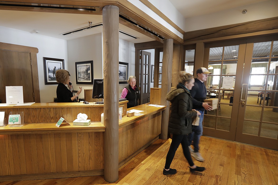 Visitors to the National Park Inn at Longmire walk away with a to-go order of food from the inn's restaurant at Mount Rainier National Park, Wednesday, March 18, 2020, in Washington state. Most national parks are remaining open during the outbreak of the new coronavirus, but many are closing visitor centers, shuttles, lodges and restaurants in hopes of containing its spread. (AP Photo/Ted S. Warren)