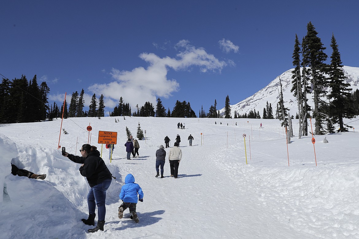 Visitors to Mount Rainier National Park walk toward the sledding area at Paradise on Wednesday, March 18, 2020, in Washington state. Most national parks are remaining open during the outbreak of the new coronavirus, but many are closing visitor centers, shuttles, lodges and restaurants in hopes of containing its spread. (AP Photo/Ted S. Warren)