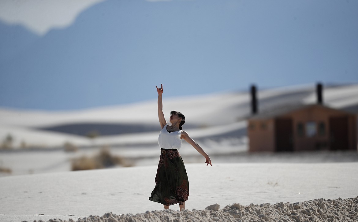 In this March 5, 2020, photograph, a woman practices modern dance while visiting White Sands National Park at Holloman Air Force Base, N.M. Most national parks are open as a refuge for Americans tired of being stuck at home because of the coronavirus. Entry fees have been eliminated, but many parks are closing visitor centers, shuttles and lodges to fight the spread of the virus. (AP Photo/David Zalubowski)