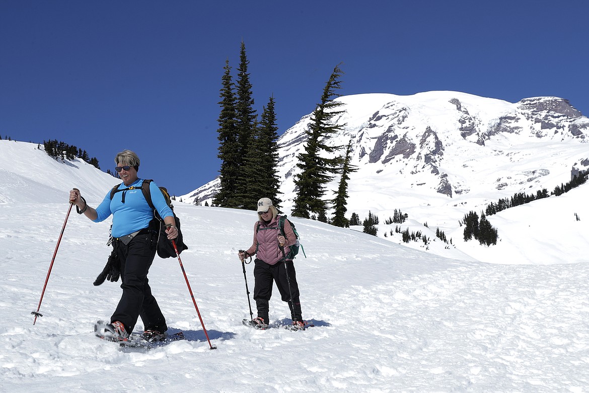 Danielle Kiechler, left, and Cathi Gouveia snowshoe above Paradise at Mount Rainier National Park, Wednesday, March 18, 2020, in Washington state. Most national parks are remaining open during the outbreak of the new coronavirus, but many are closing visitor centers, shuttles, lodges and restaurants in hopes of containing its spread. Both women work at schools in Puyallup, Wash., that are currently closed due to the virus outbreak. (AP Photo/Ted S. Warren)