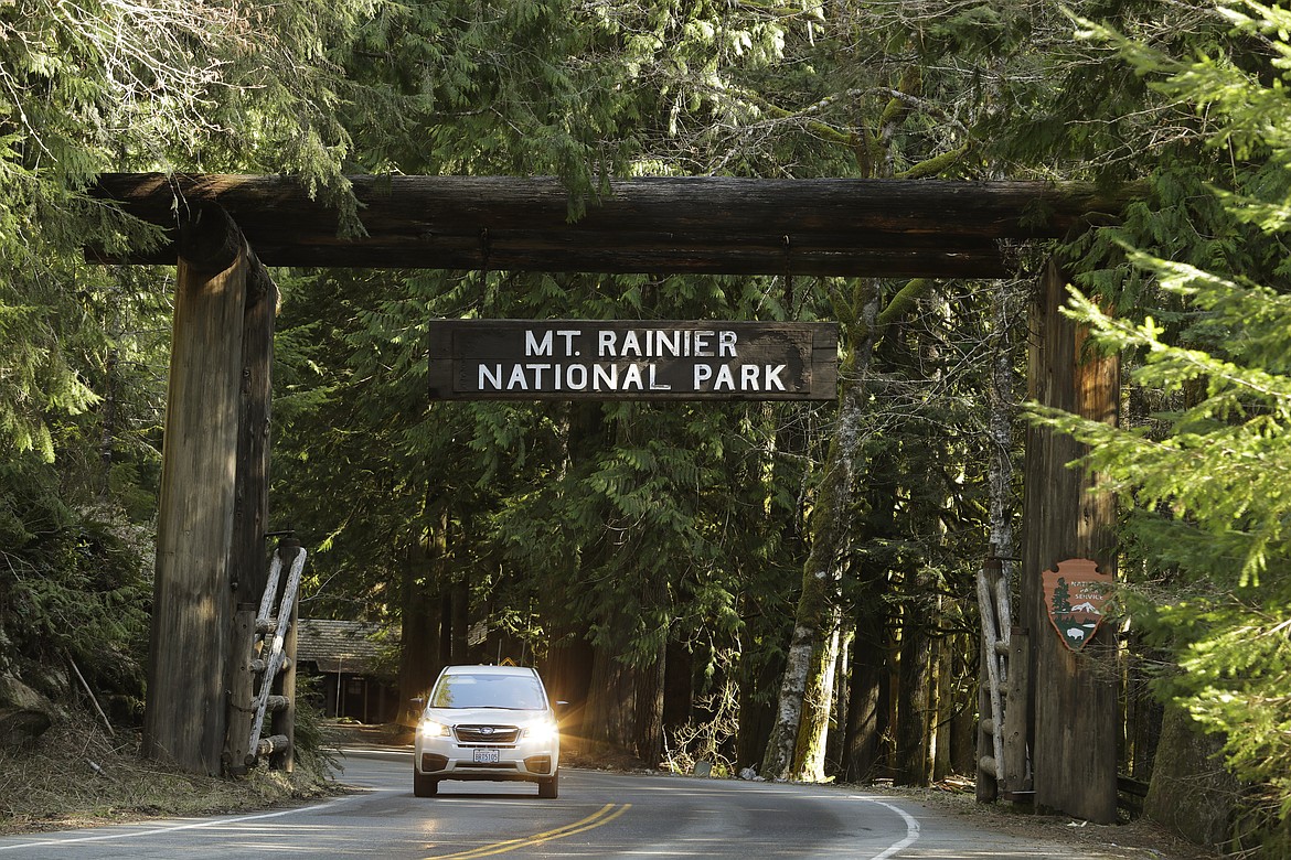 A car passes through the entrance to Mount Rainier National Park, Wednesday, March 18, 2020, in Washington state. Most national parks are remaining open during the outbreak of the new coronavirus, but many are closing visitor centers, shuttles, lodges and restaurants in hopes of containing its spread. (AP Photo/Ted S. Warren)