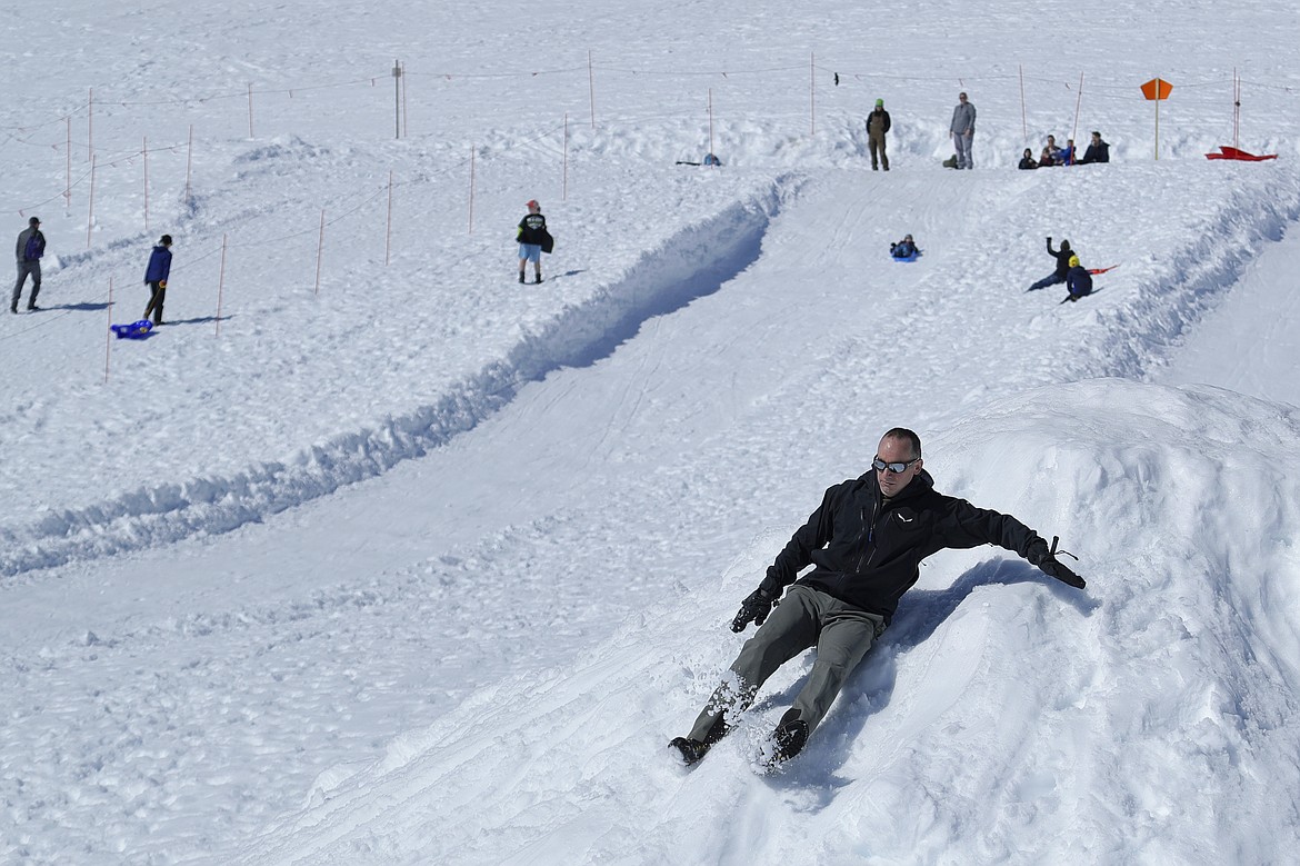 Jon Penoyar, lower right, slides without a sled near the sledding area at Paradise at Mount Rainier National Park, Wednesday, March 18, 2020, in Washington state. Most national parks are remaining open during the outbreak of the new coronavirus, but many are closing visitor centers, shuttles, lodges and restaurants in hopes of containing its spread. Penoyar said he and his family brought camping food to eat on this visit to the park since the Henry M. Jackson Visitor Center was closed. (AP Photo/Ted S. Warren)
