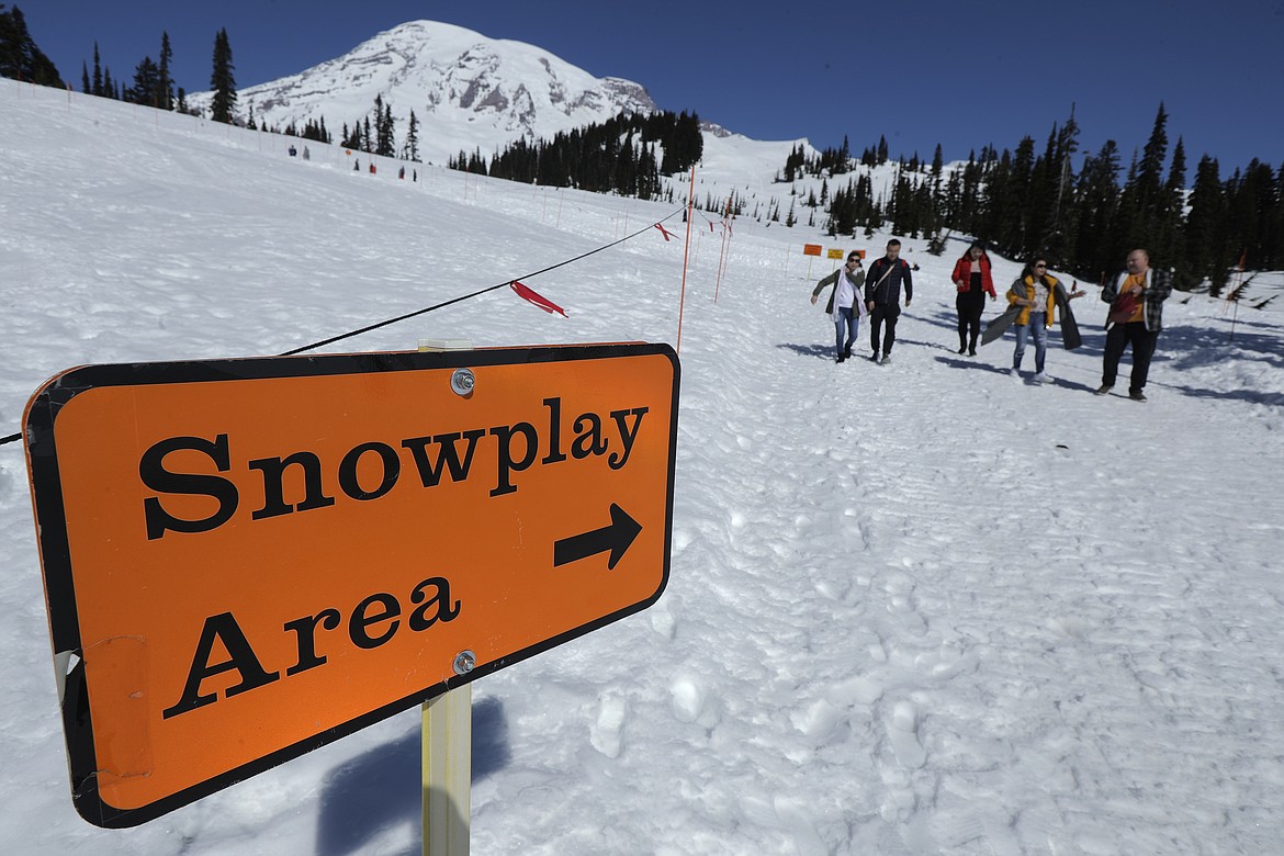 Visitors to Mount Rainier National Park walk away from the sledding area at Paradise, Wednesday, March 18, 2020, in Washington state. Most national parks are remaining open during the outbreak of the new coronavirus, but many are closing visitor centers, shuttles, lodges and restaurants in hopes of containing its spread. (AP Photo/Ted S. Warren)