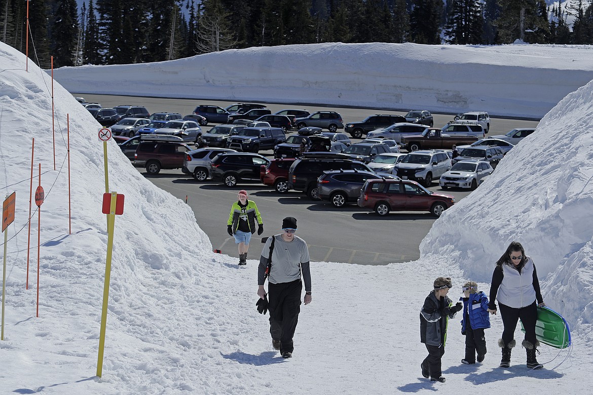 Visitors to Mount Rainier National Park walk toward the sledding area at Paradise, Wednesday, March 18, 2020, in Washington state. Most national parks are remaining open during the outbreak of the new coronavirus, but many are closing visitor centers, shuttles, lodges and restaurants in hopes of containing its spread. (AP Photo/Ted S. Warren)