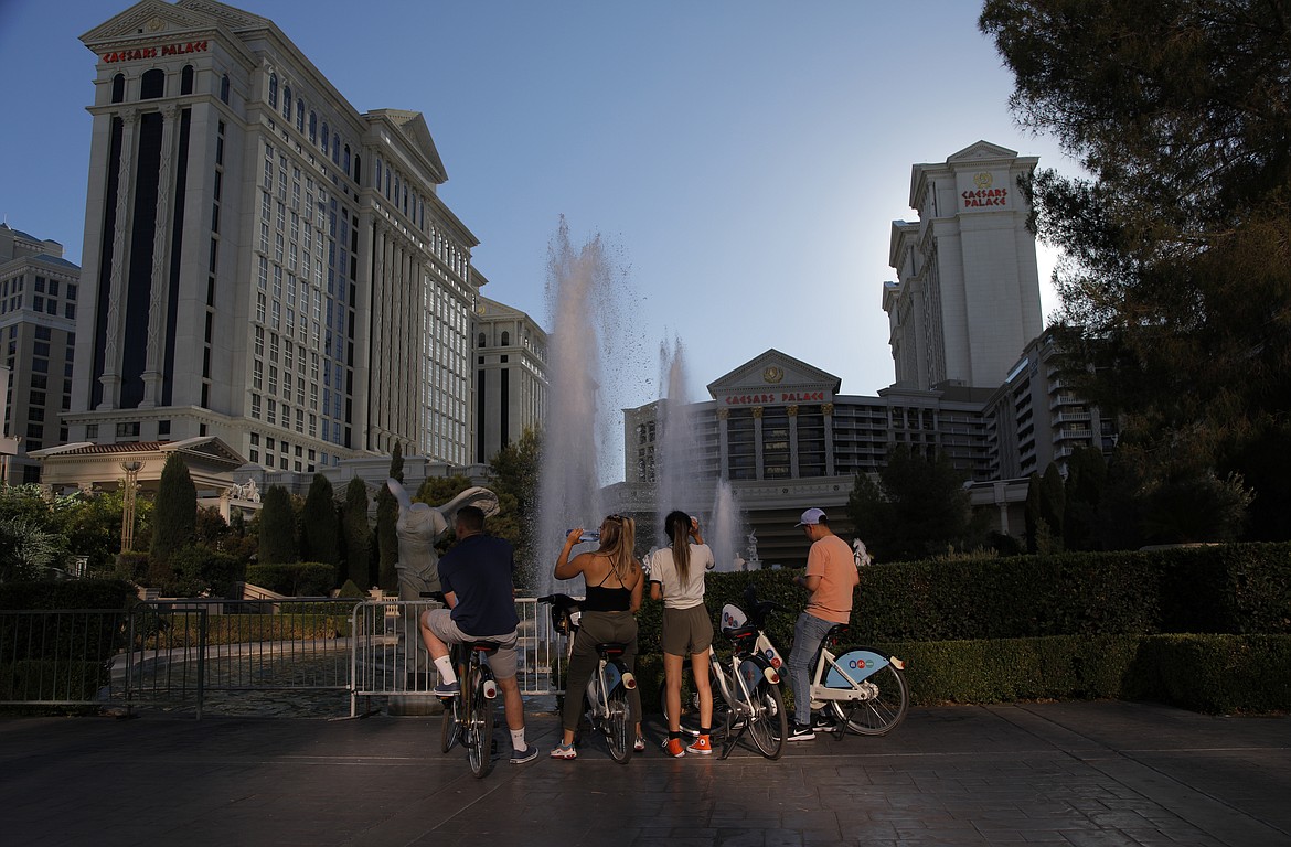 People stop to look at the fountains at Caesars Palace hotel and casino along the Las Vegas Strip devoid of the usual crowds during the coronavirus pandemic, Tuesday, May 26, 2020, in Las Vegas. (AP Photo/John Locher)